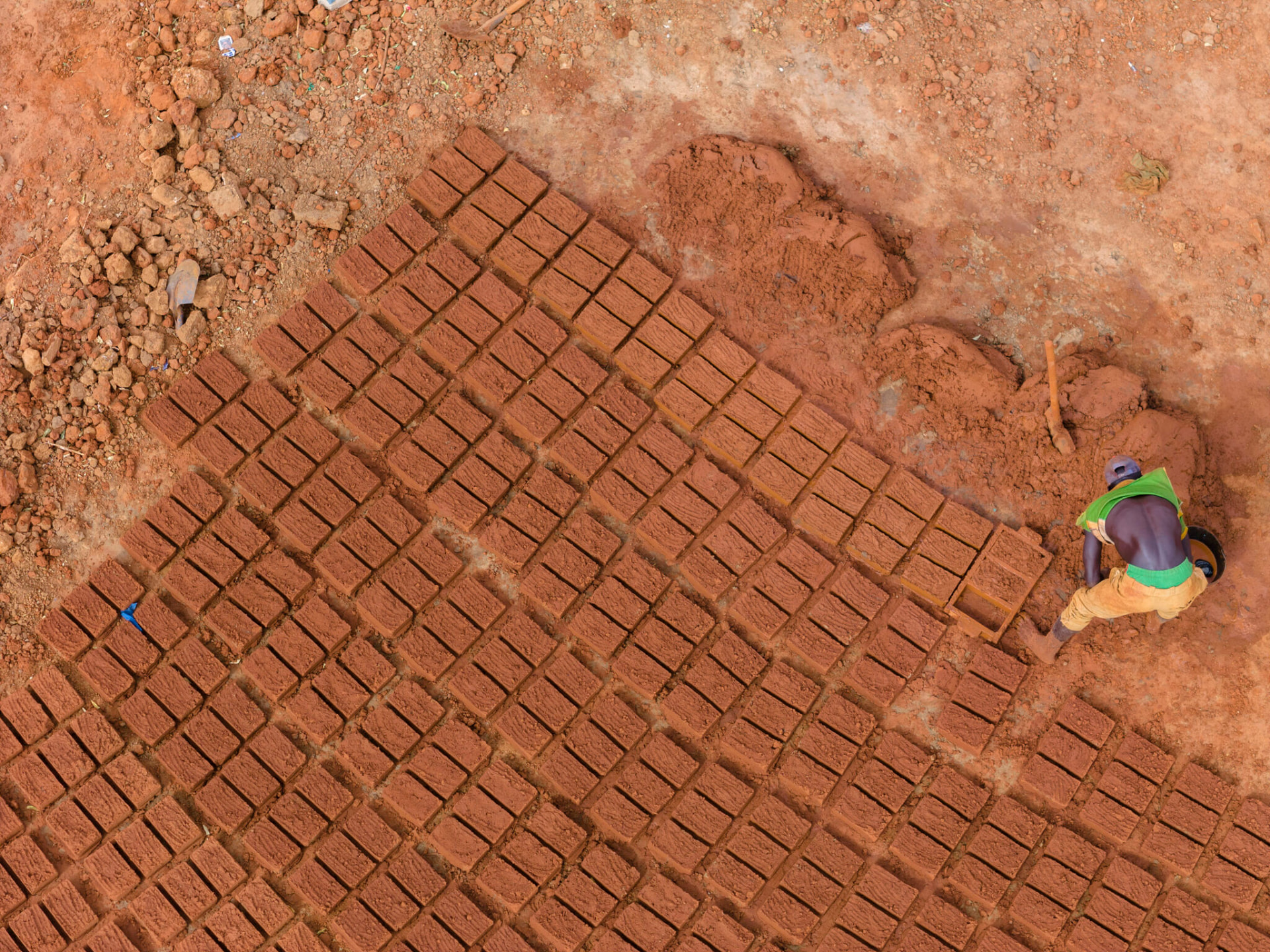 Aerial view of a worker laying out mud bricks to dry in West Africa