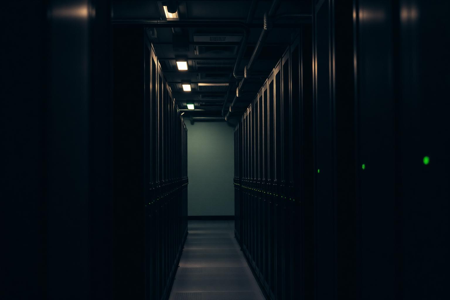 Dim server room aisle with rows of racks and small green indicator lights